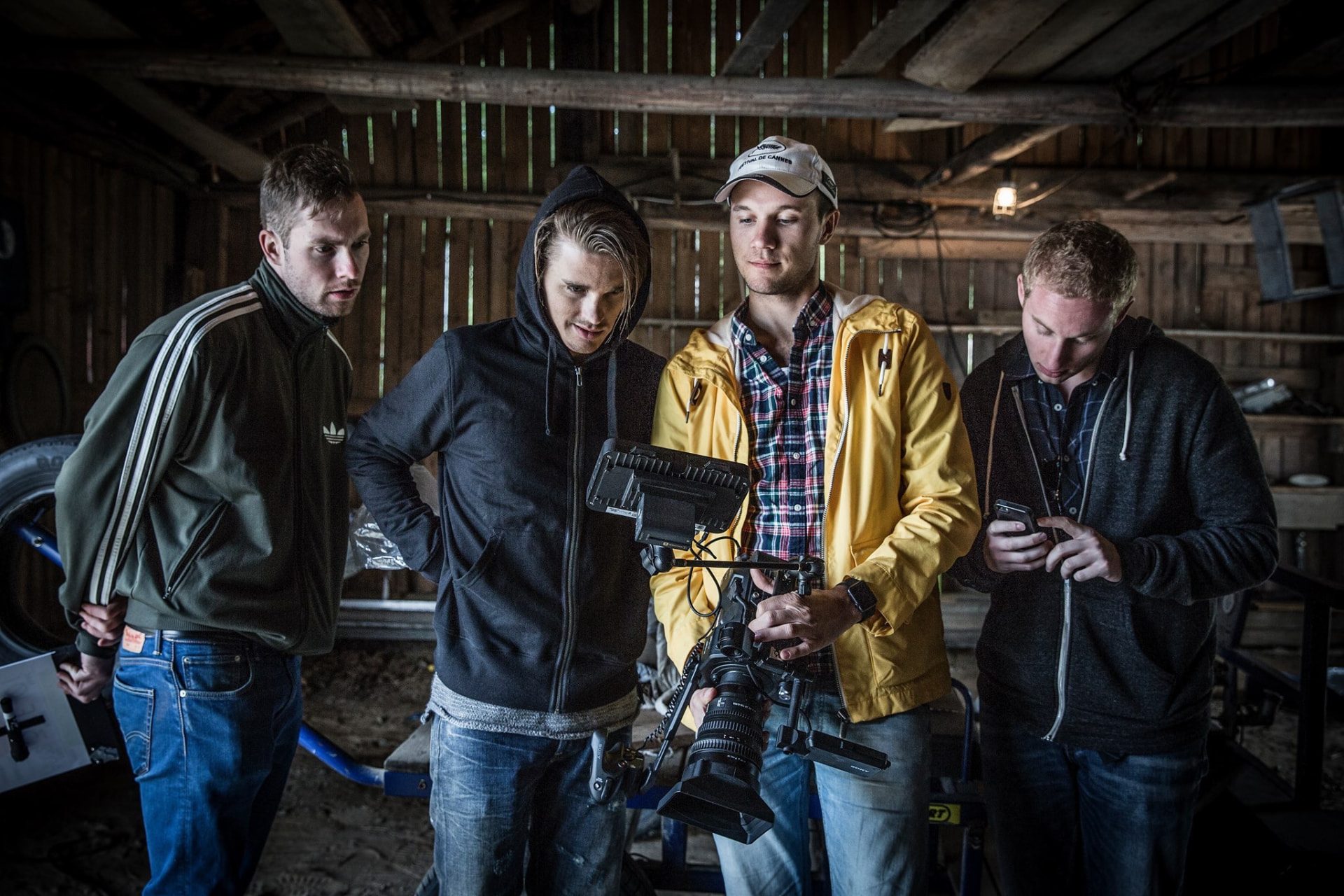 Filmteam samlat kring en monitor i en lada under inspelning